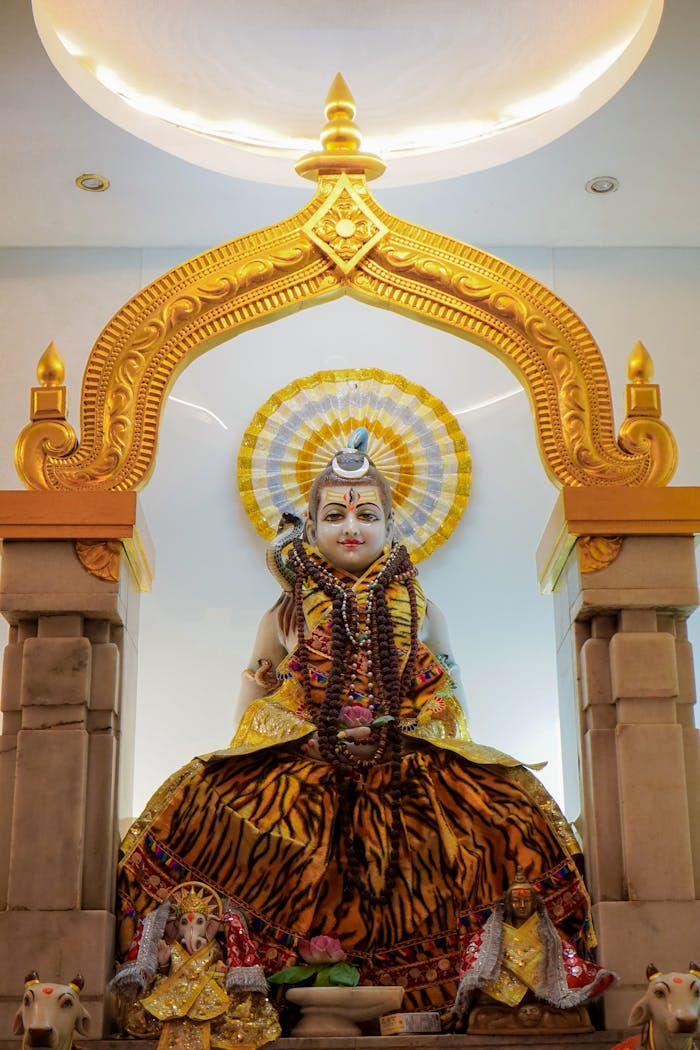 Vibrant Hindu deity statue adorned in temple shrine with ornate gold arch.