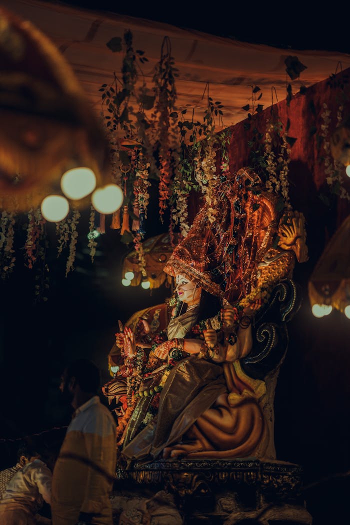 A vibrant, detailed Ganesh idol displayed at an evening festival with hanging floral decorations.