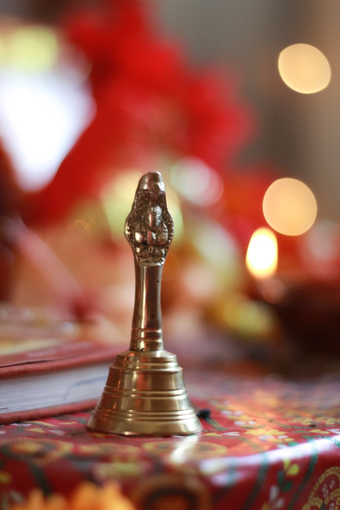 Detailed shot of a brass bell on a decorated cloth, symbolizing Hindu spirituality and rituals.